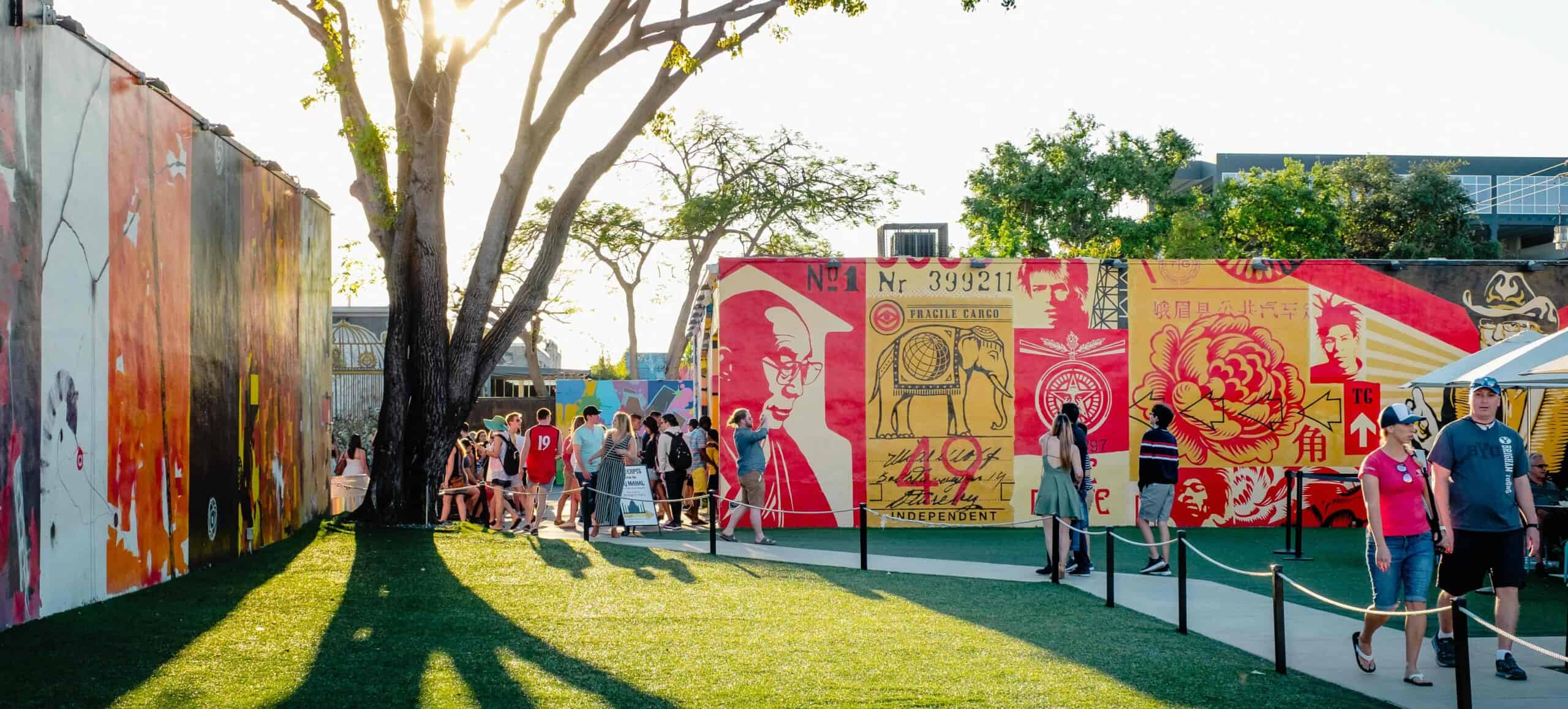 People viewing vibrant mural art in an outdoor park setting.