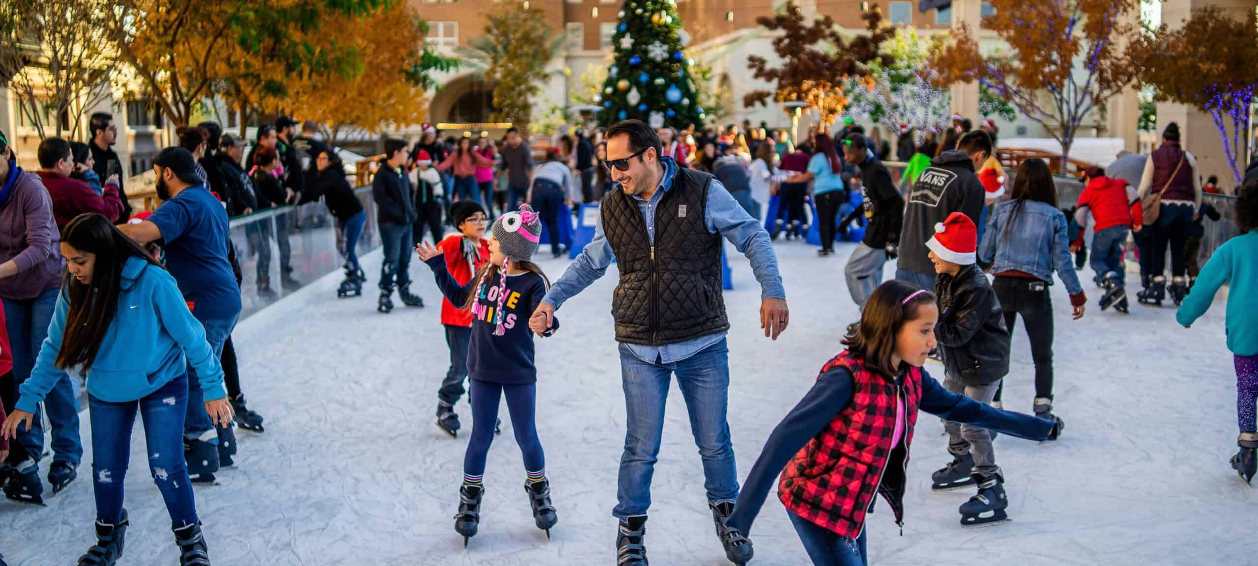 People enjoying ice skating at a festive outdoor rink during the holiday season.