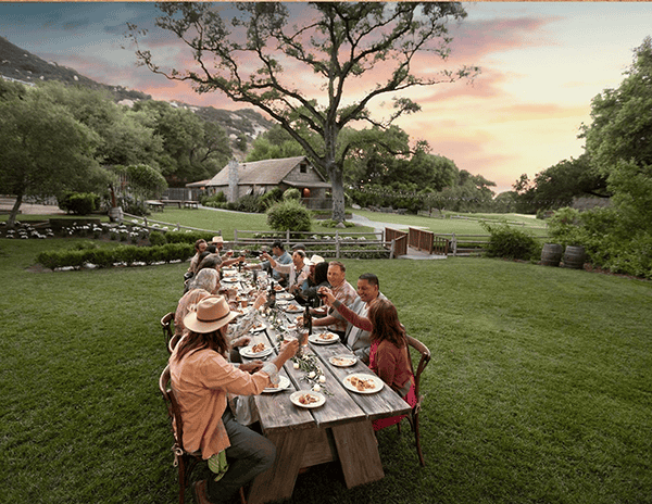 People enjoying a fine outdoor dinner at sunset in a scenic American landscape.