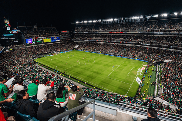 Crowd watching a soccer game at a large stadium at night.