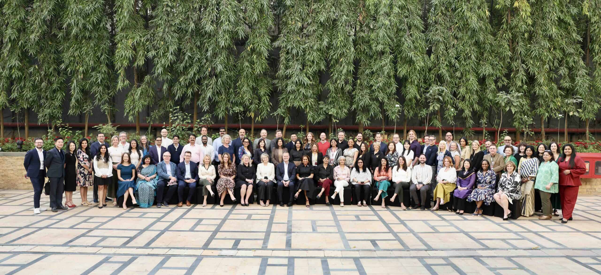 Large group of diverse professionals gathered outdoors for a group photo.