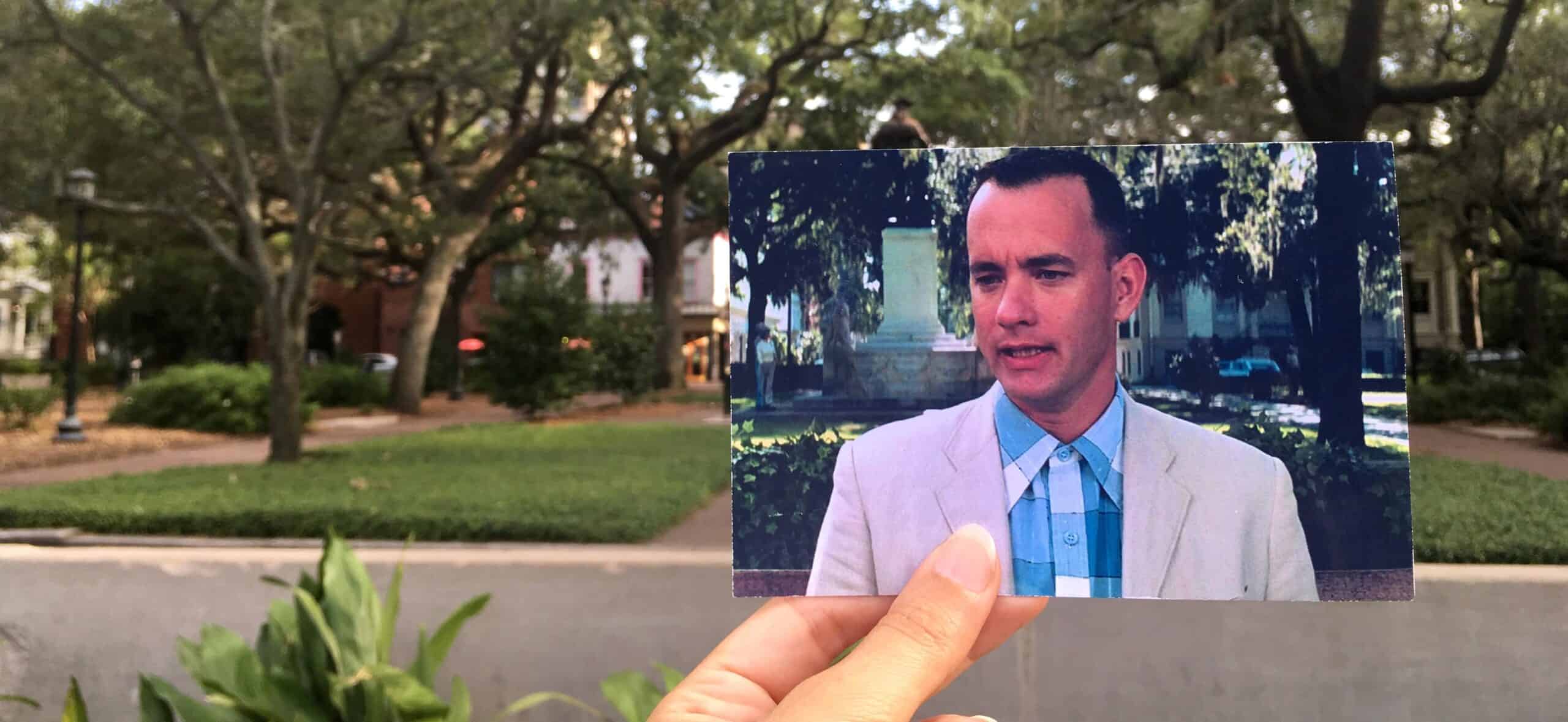 Man holding a transparent photo card outdoors in a park setting.