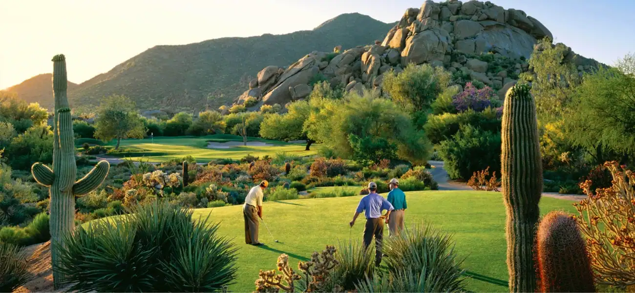 Desert golf course with cacti and mountains in the background.