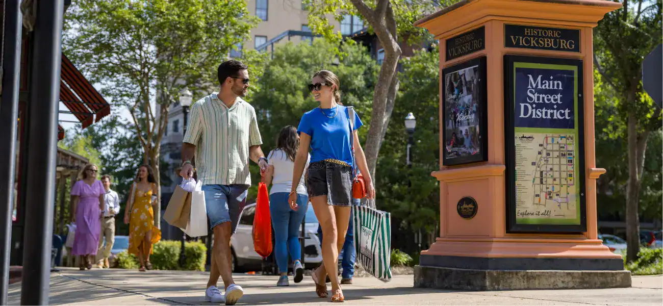 Tourists walking in Vicksburg Main Street District with historic signage.